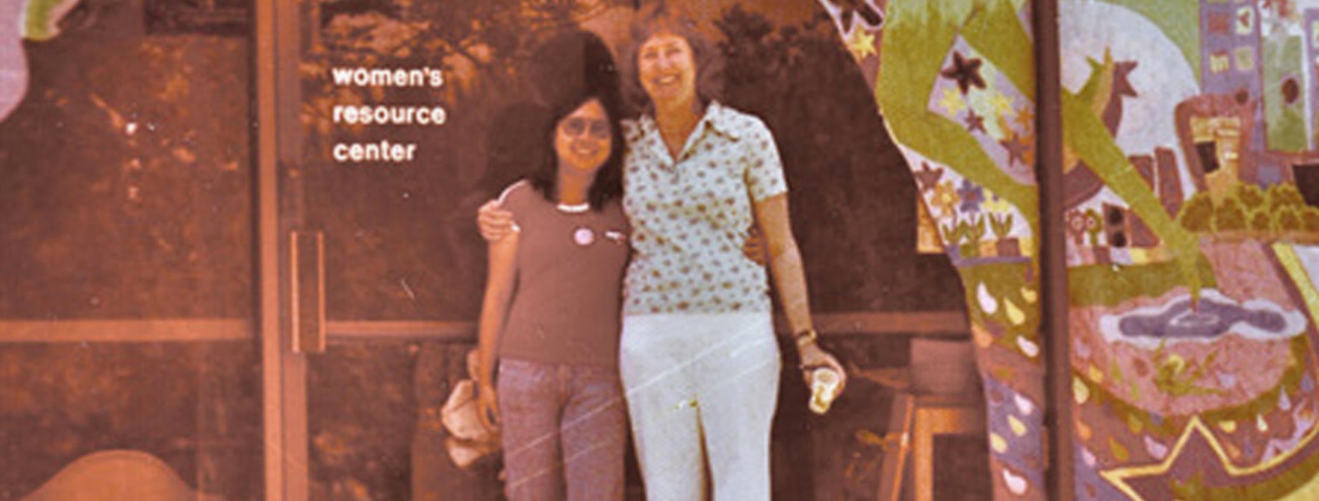 Two women standing side-by-side in front of the women's resource center in the 1970s.