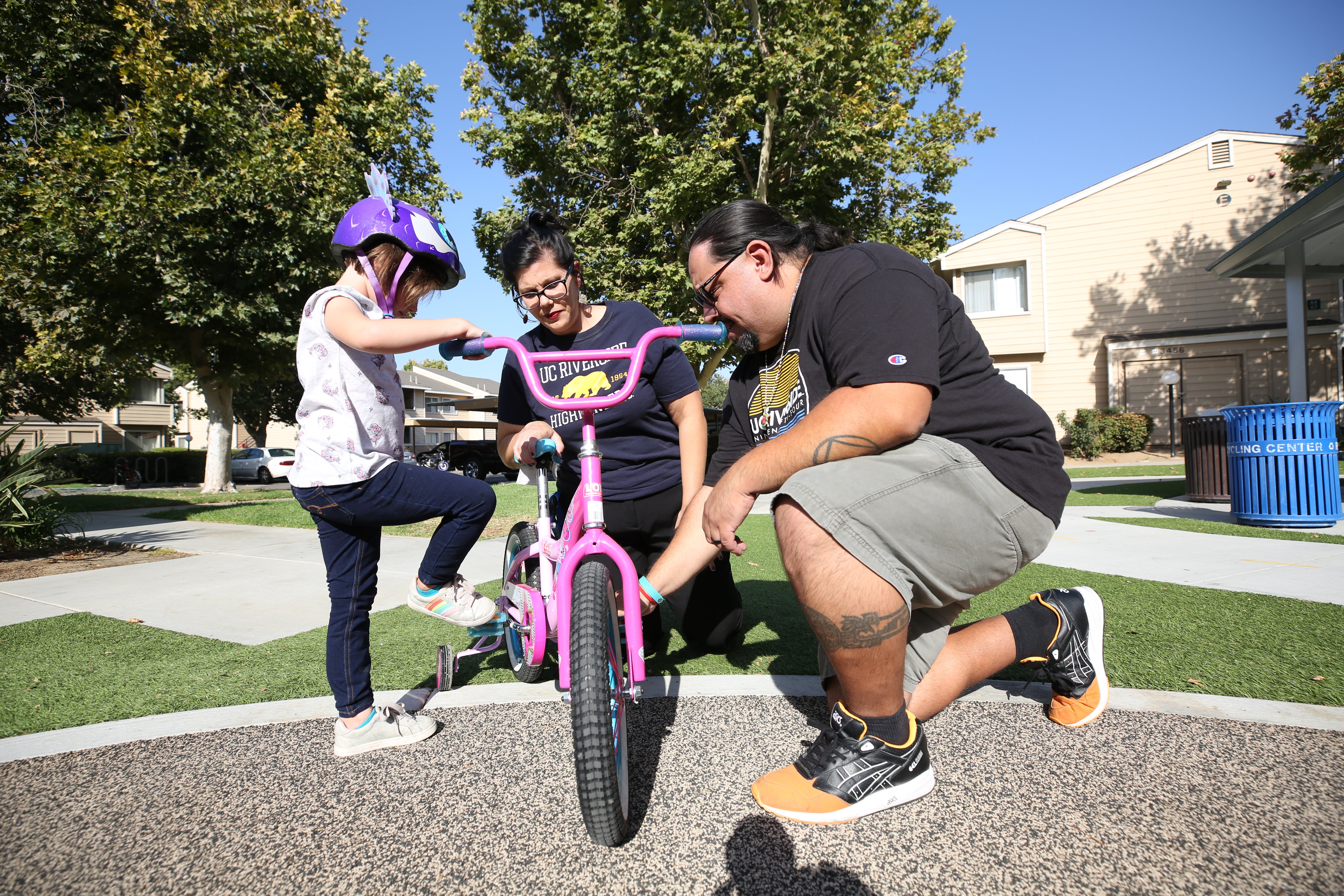 two adults helping a child repair their bike