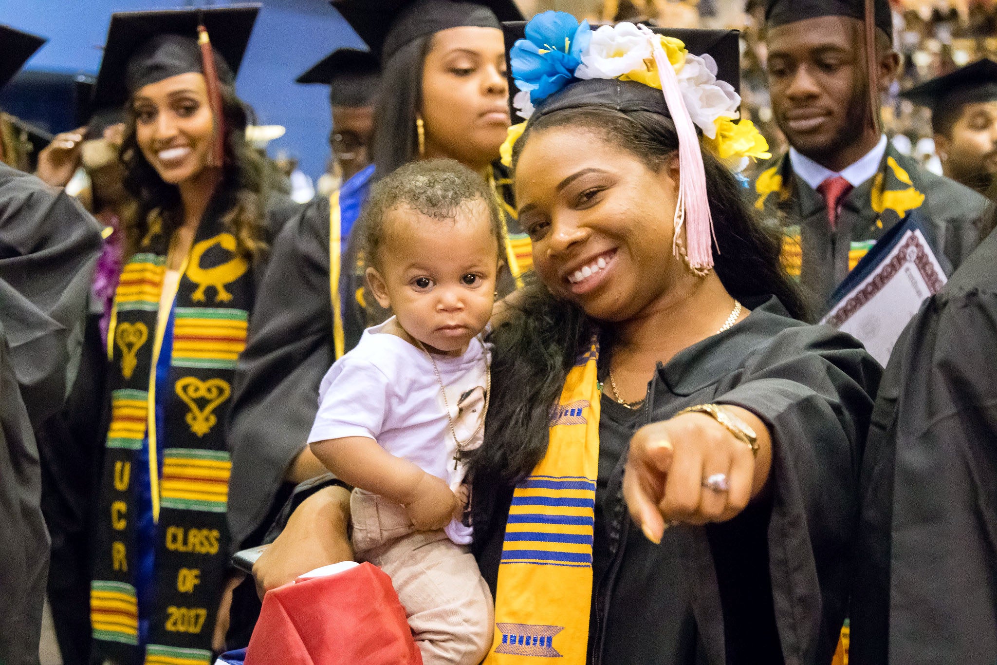 Student at graduation with a baby in her arms.